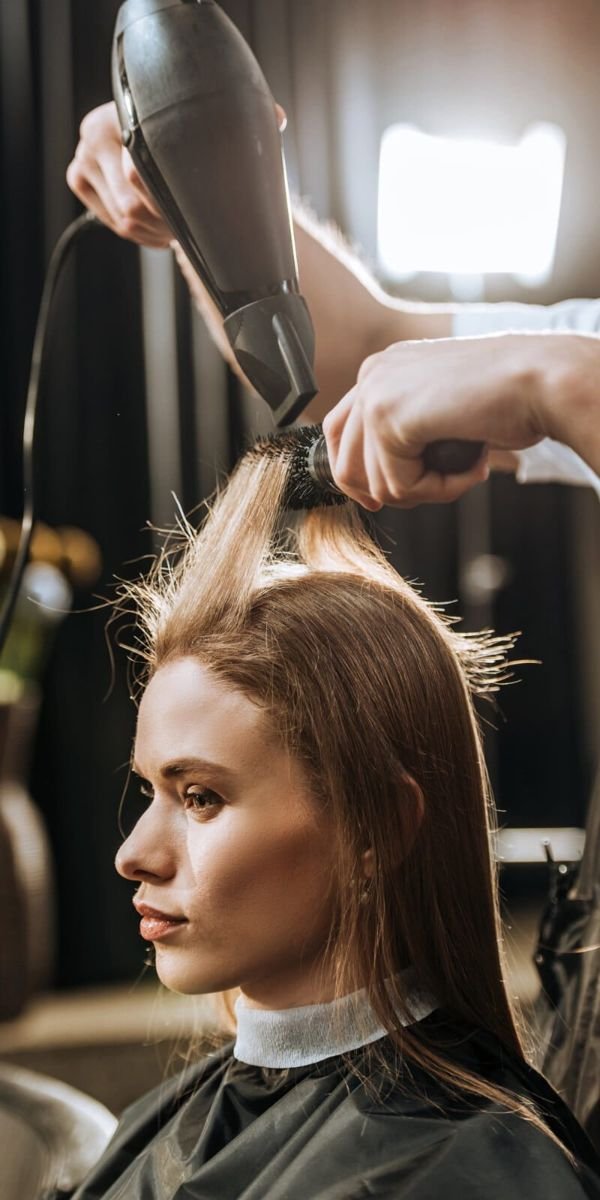 Haare werden mit Rundbürste und Föhn gestylt